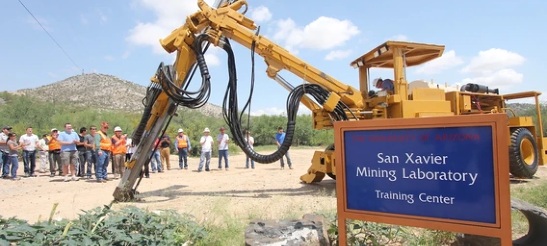 a group gathered near the san xavier mining laboratory with a large mining machine nearby