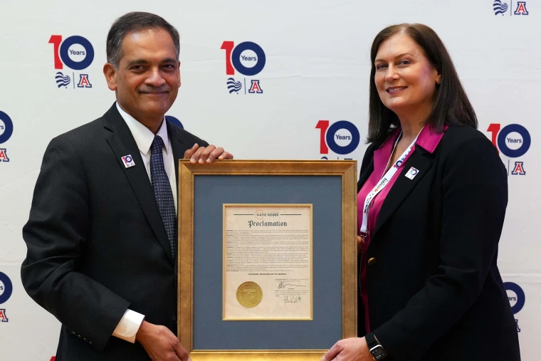 two people pose with a framed proclamation