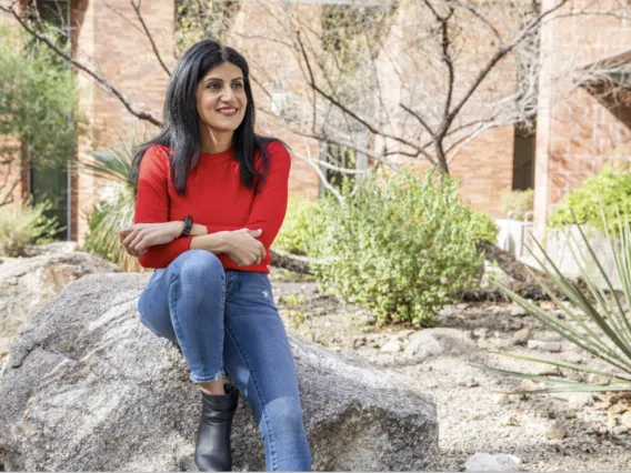 Malak Tfaily sits on a rock outside of her lab