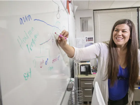 Tally Largent-Milnes works at a whiteboard 