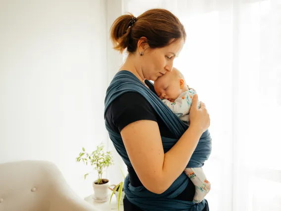 Image of a mother holding a child in a baby carrier