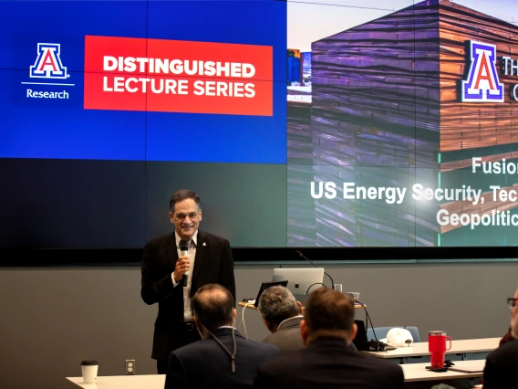 President Garimella speaks in front of a large screen.