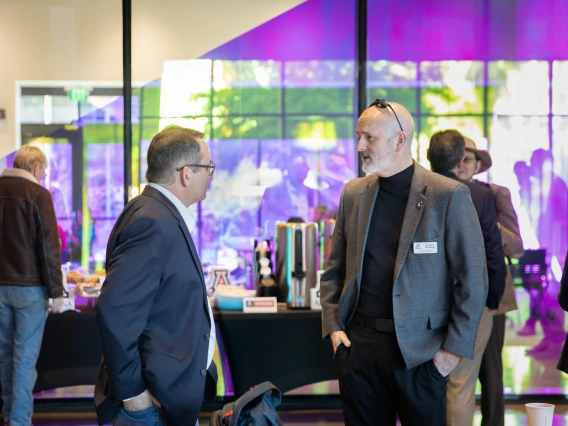 Men in blazers talk to each other in the lobby of the Grand Challenges Research Building.