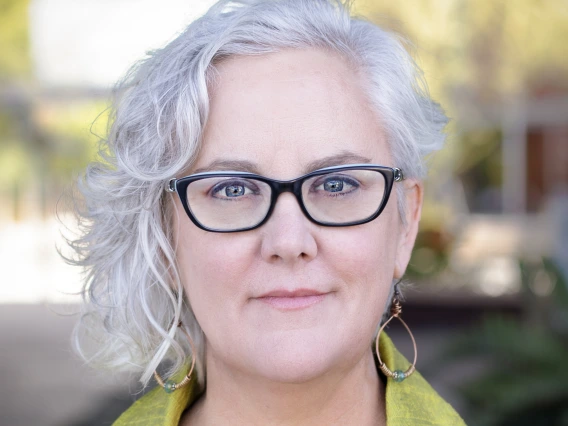 woman with wavy white hair in black glasses and chartreuse blazer