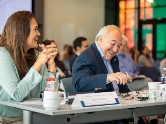 Two people smile sitting at a table.