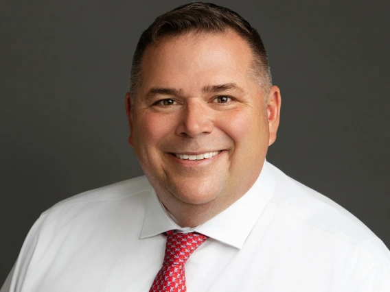 smiling man wearing a white collared shirt and red with white pattern tie