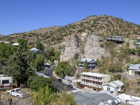 Looking down at the town of Bisbee, Arizona, showing main road, houses, hotel, store, with mountains in background.