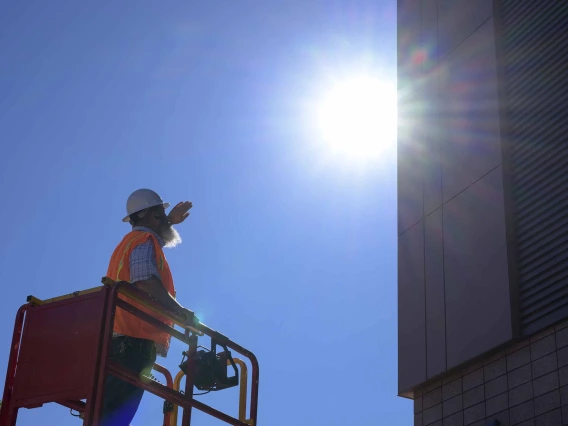 A construction worker shields himself from the sun with his hand