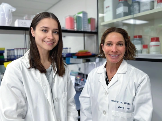 Jennifer Stern and Kassandra Bruner, wearing white coats in a lab setting