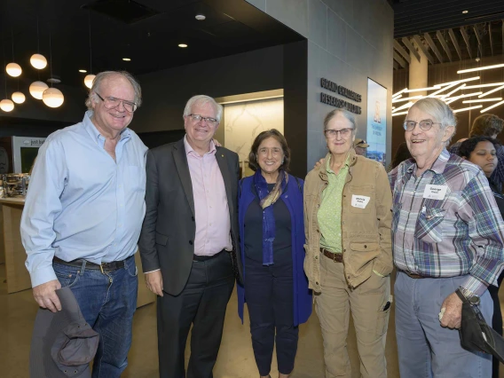 Five professors stand beside each other smiling during a reception. 