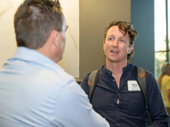 Two standing men talk with each other.