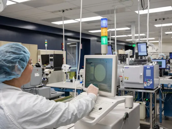 woman in protective gear working with a machine in a white lab