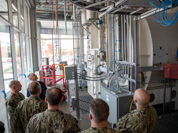 Mark Matsuko, director of operations and facilities for the ARB, leads a delegation from U.S. Fleet Forces Command through the Applied Research Building.
