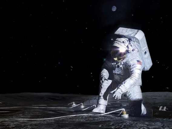 Astronaut kneels on the lunar surface to install technology