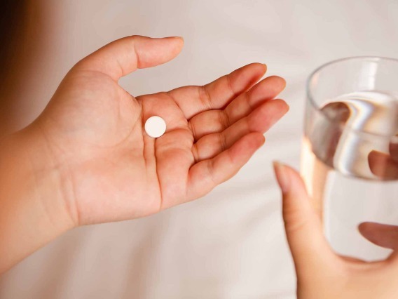 a person holding a pill and a glass of water
