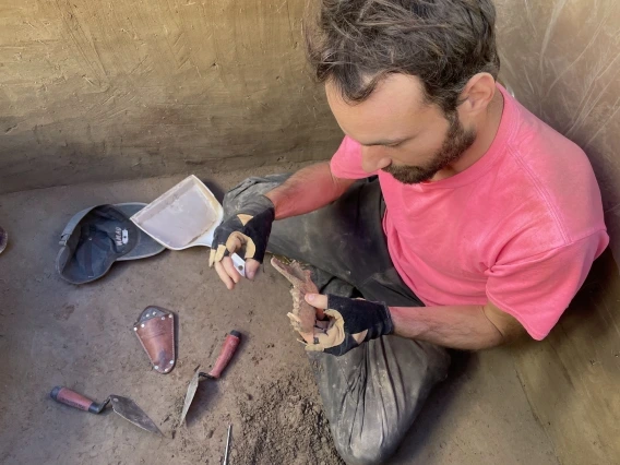 François Lanoë sitting in an archaeological excavation site holding a jawbone