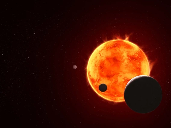 Artist's illustration of the TRAPPIST system shows the star as an orange glowing ball with four of its seven planets orbiting around it. 