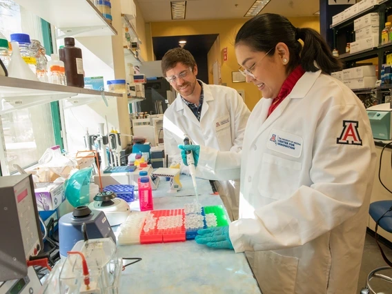 two people smiling and working inside a lab at UACI