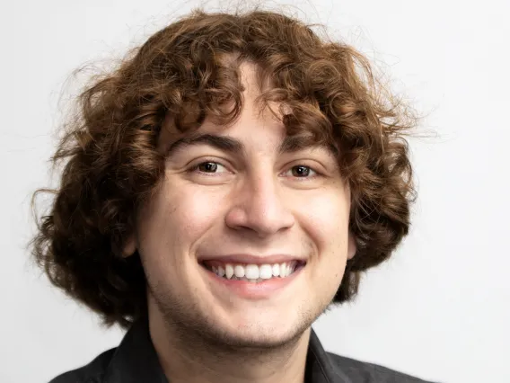 portrait of Michael Pisetsky against a light gray background, wearing a black button down shirt and smiling