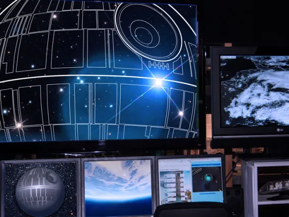 Storm trooper looking at a bank of computers with the death star plans on the computer screens