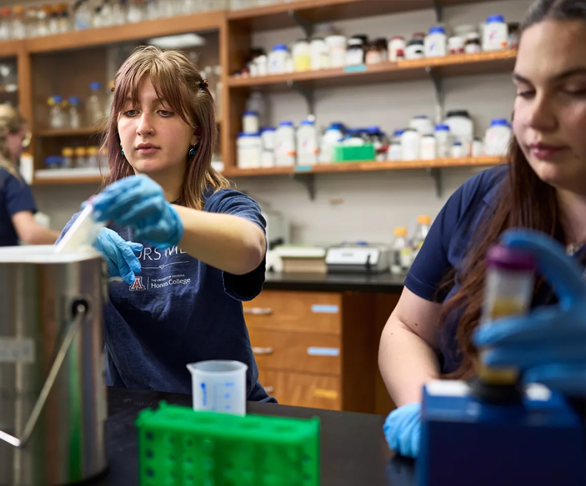 Two young women in protective gloves in a lab setting