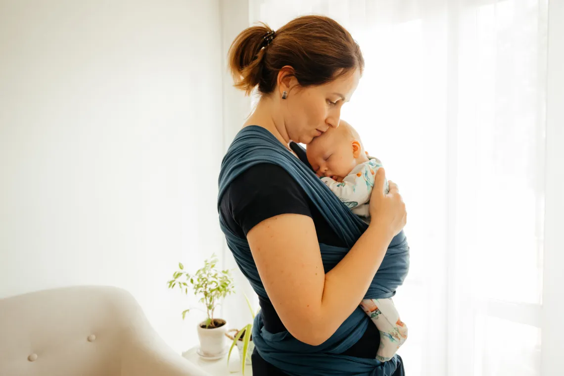 Image of a mother holding a child in a baby carrier