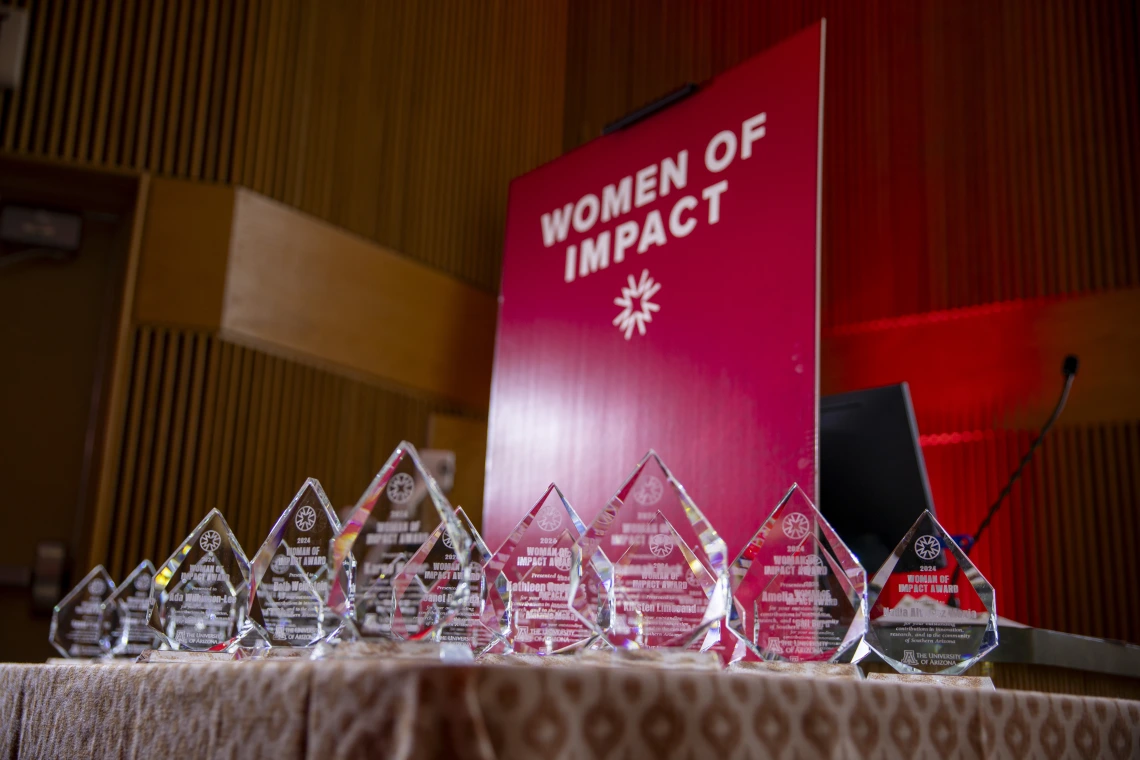 A table of awards in front of a red banner.