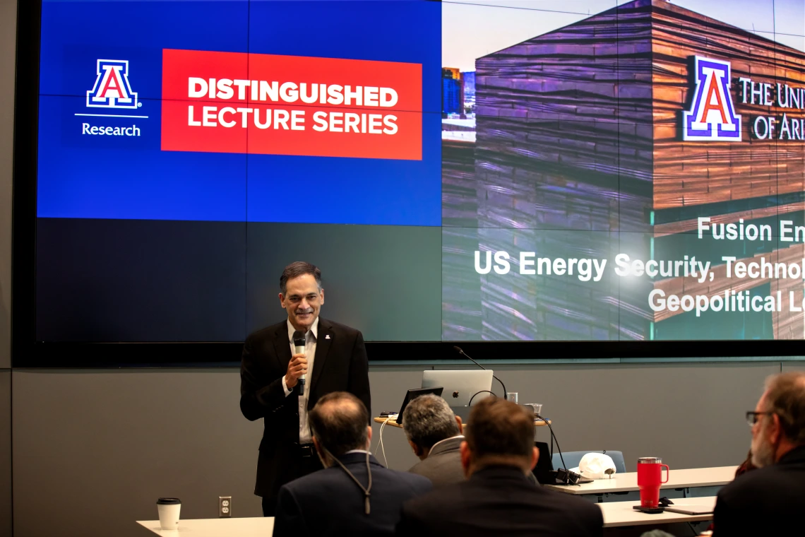 President Garimella speaks in front of a large screen.