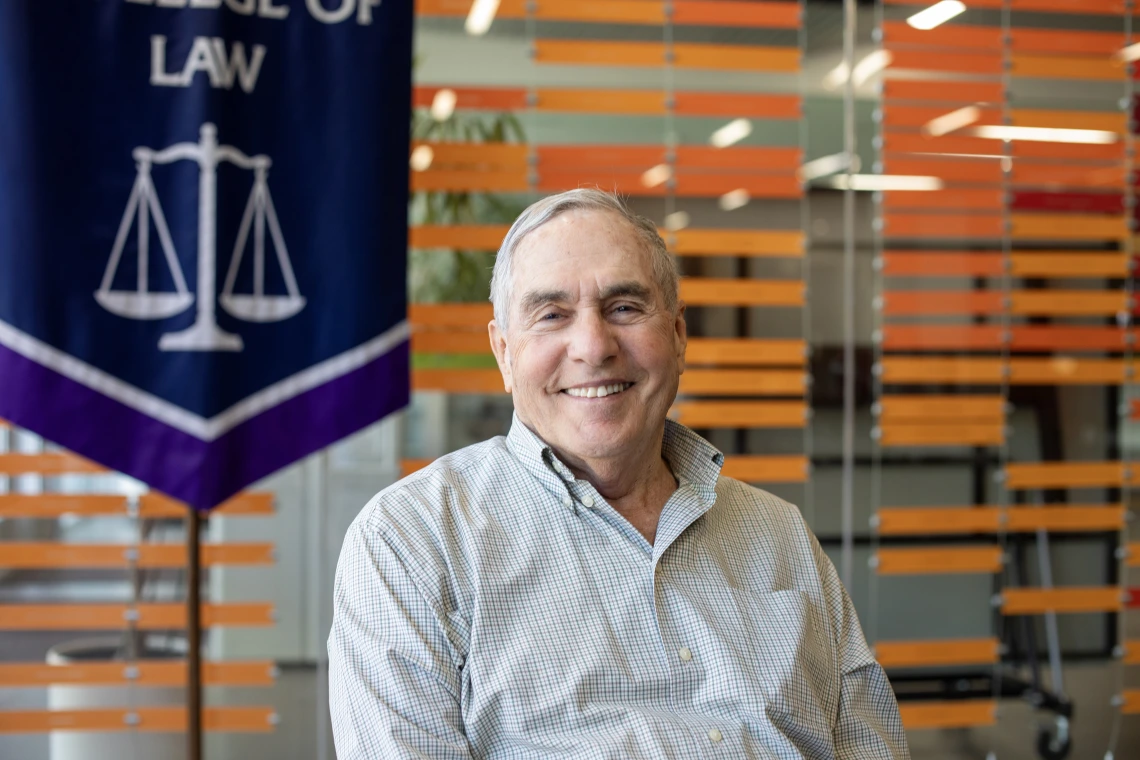 image of smiling man in front of school of law banner