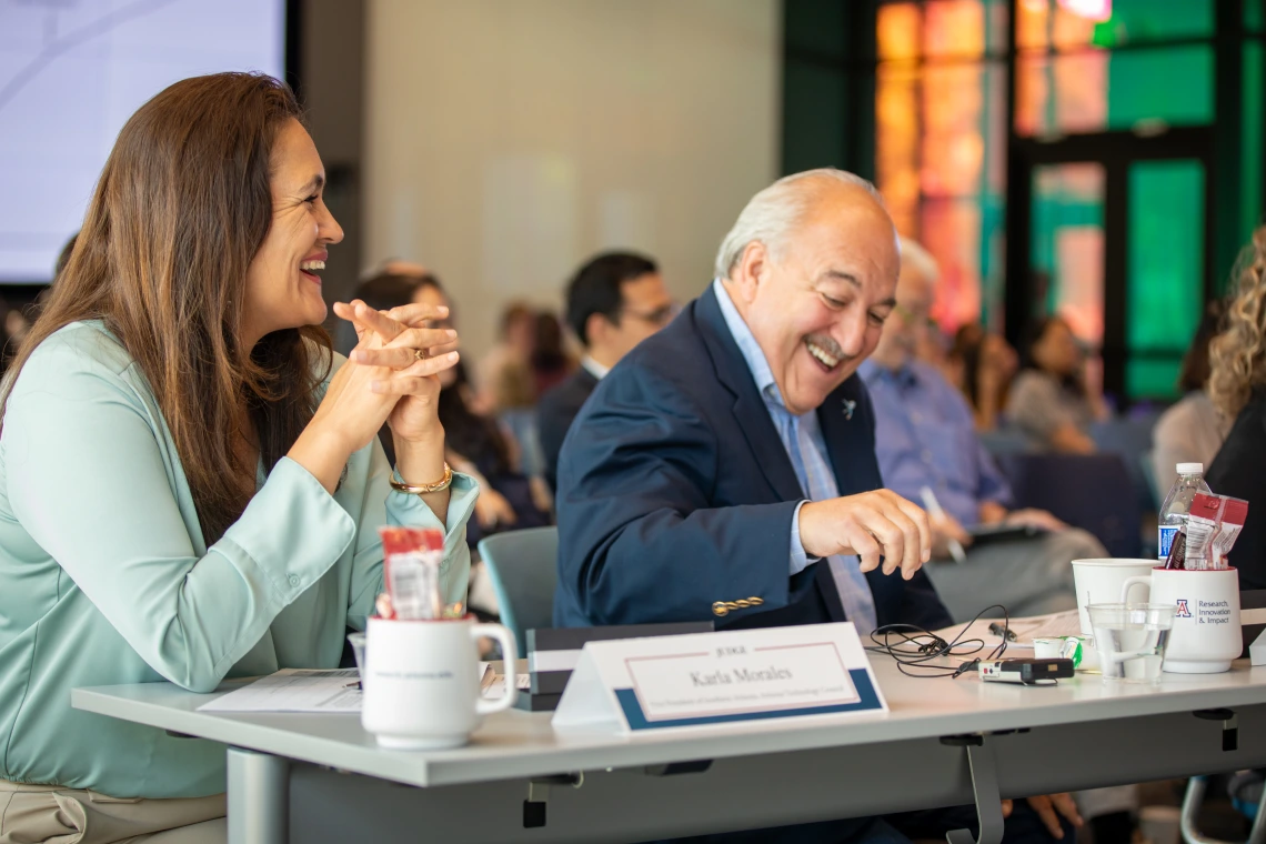 Two people smile sitting at a table.