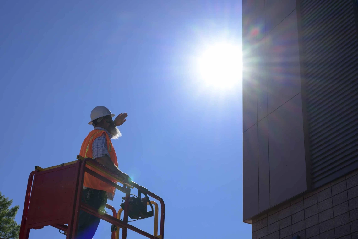 A construction worker shields himself from the sun with his hand