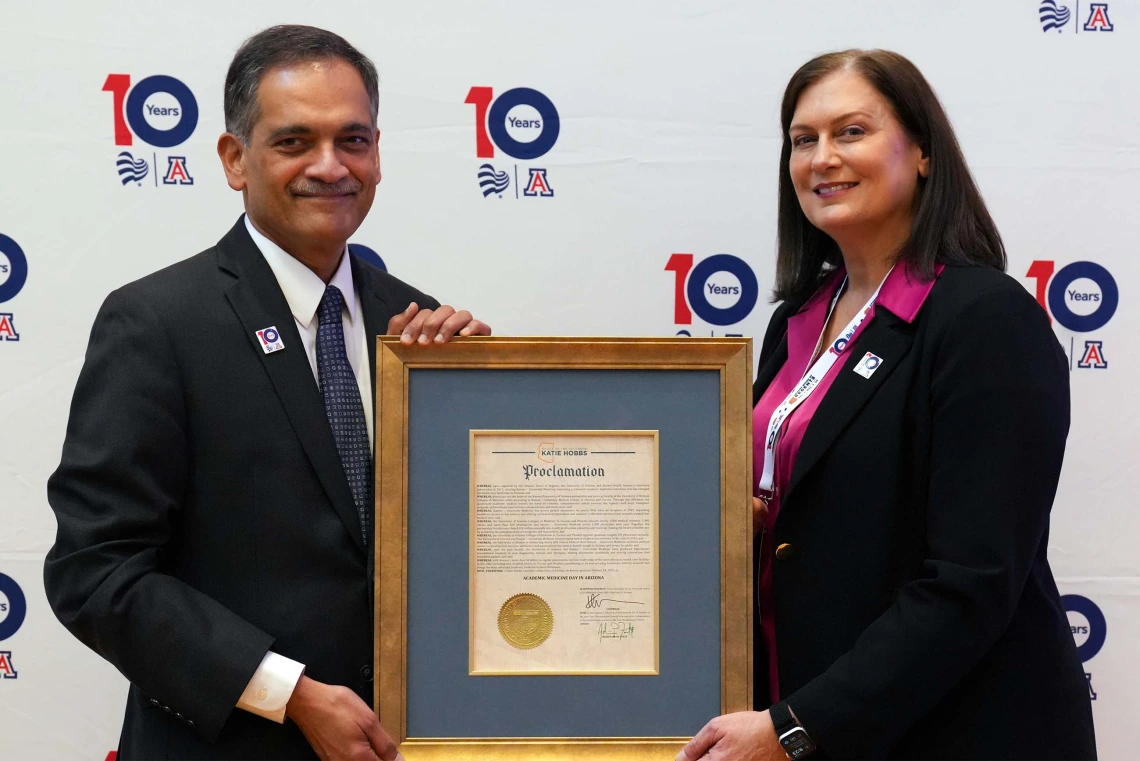 two people pose with a framed proclamation