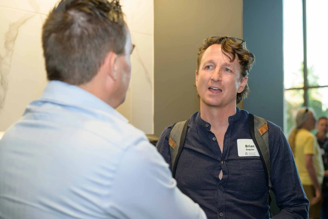 Two standing men talk with each other.