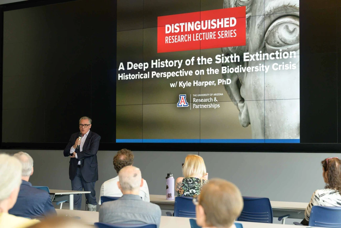 View from the back of a lecture hall over the heads of the audience with a projection of a face from a classic marble sculpture and text that reads, “Distinguished Research Lecture Series”. 