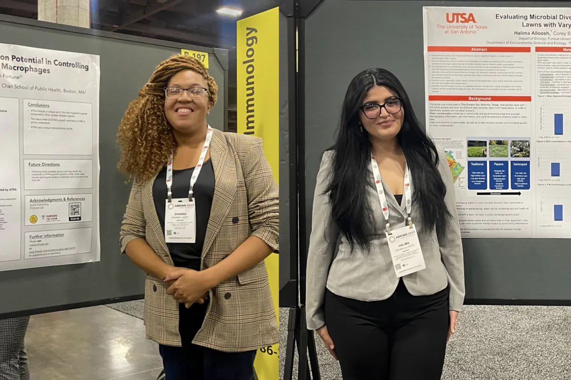 Two students stand next to posters at scientific conference