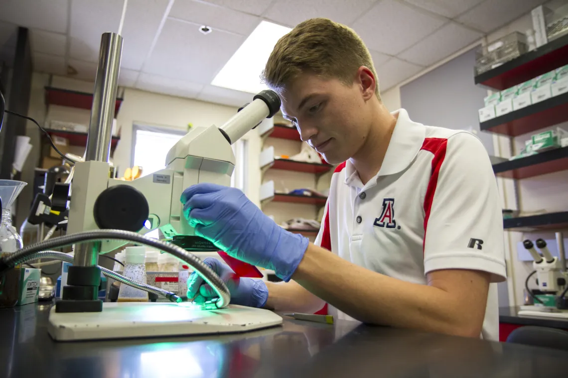 Briggs Carhart examining a sample under a microscope.