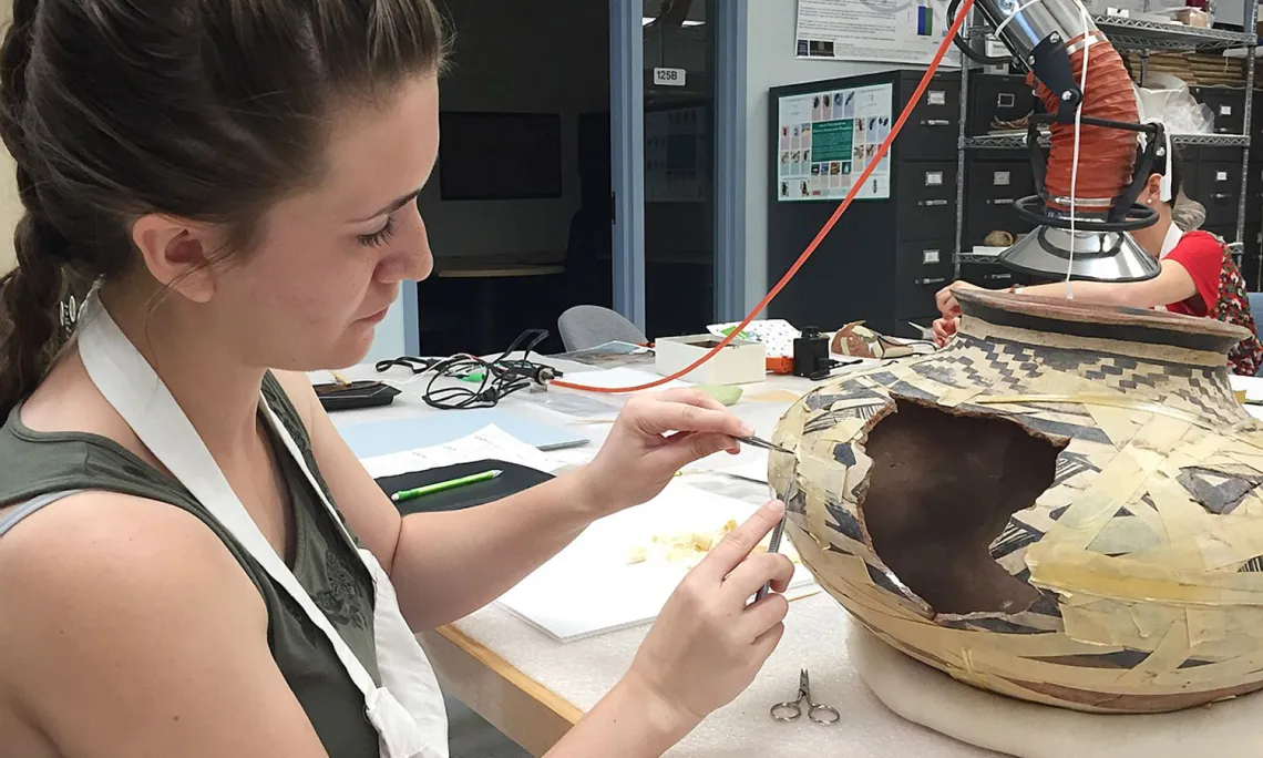 Art conservationist Sophie Church handles a piece of pottery at the Arizona State Museum. 