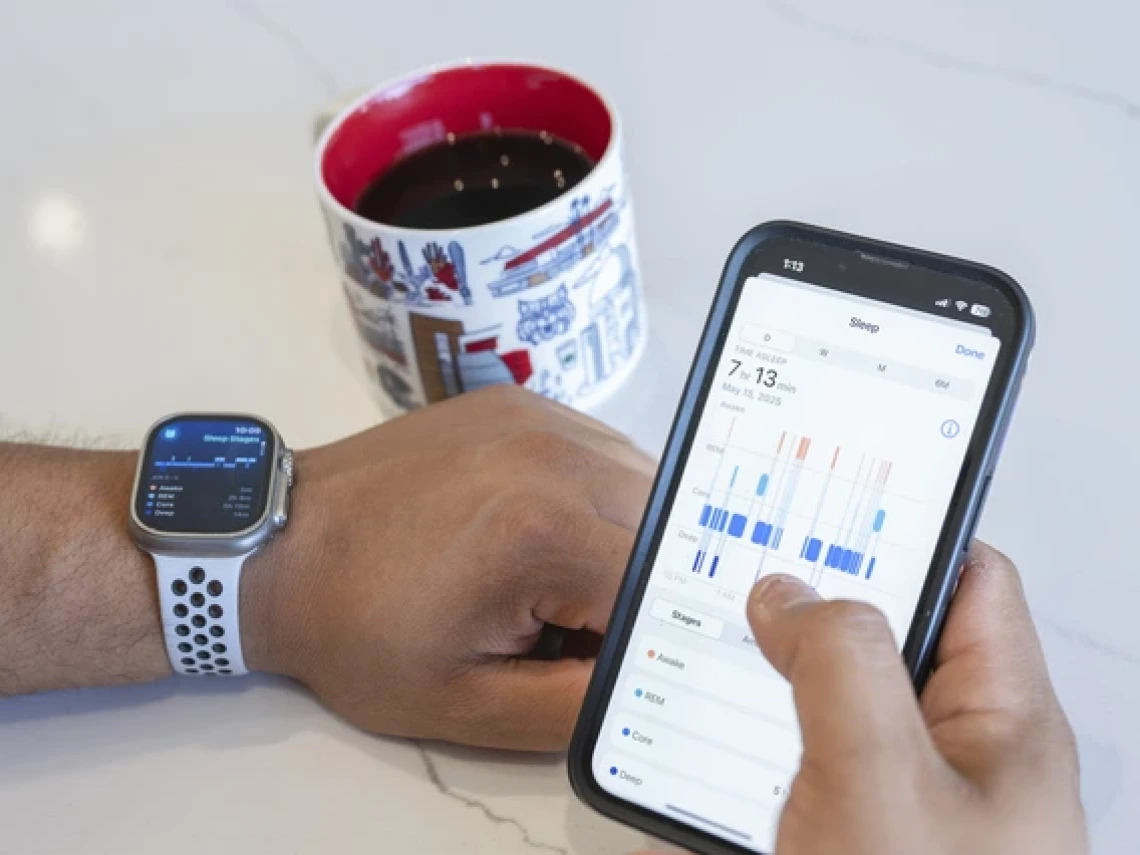 a close-up of a person's wrists and hands with a smart watch on one wrist and a smartphone in the other hand displaying sleep data