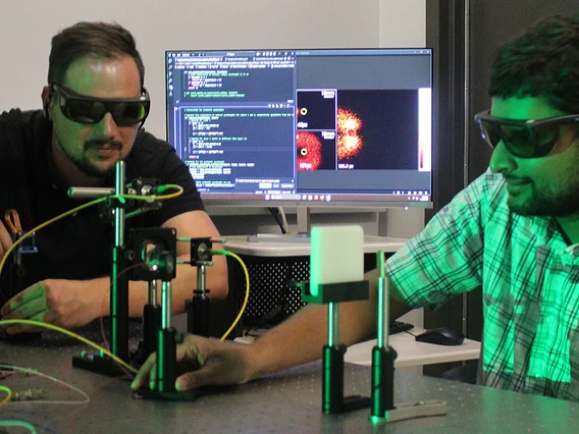 Wearing dark, tinted eye protection goggles, Willomitzer and a postdoctoral researcher set up instrumentation on an optical lab bench. 