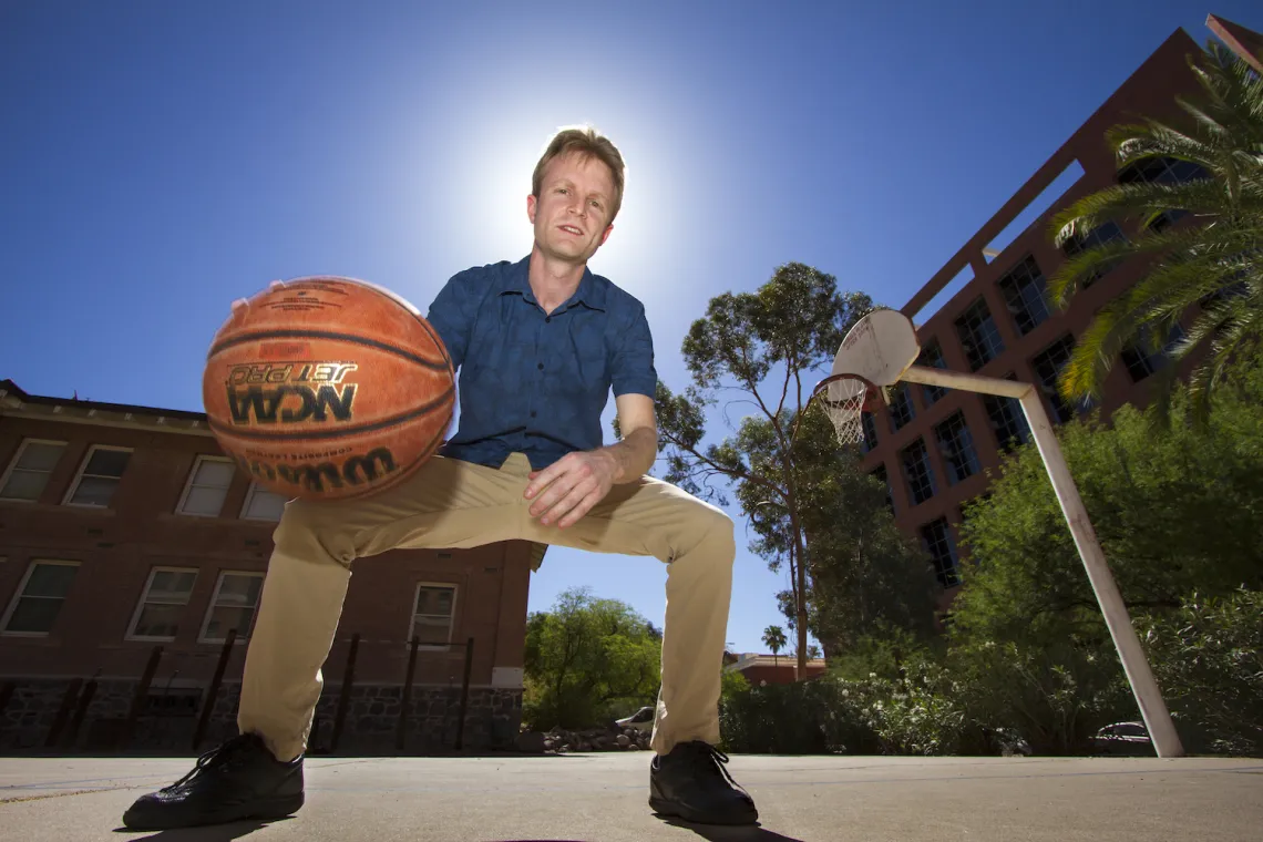 UA physicist Sam Gralla dribbles a ball on the basketball court.