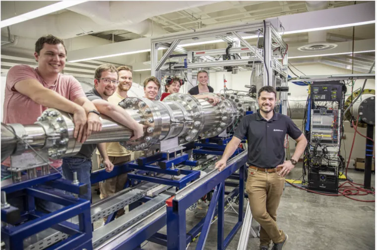 Students stand behind equipment next to Alex Craig in his lab.