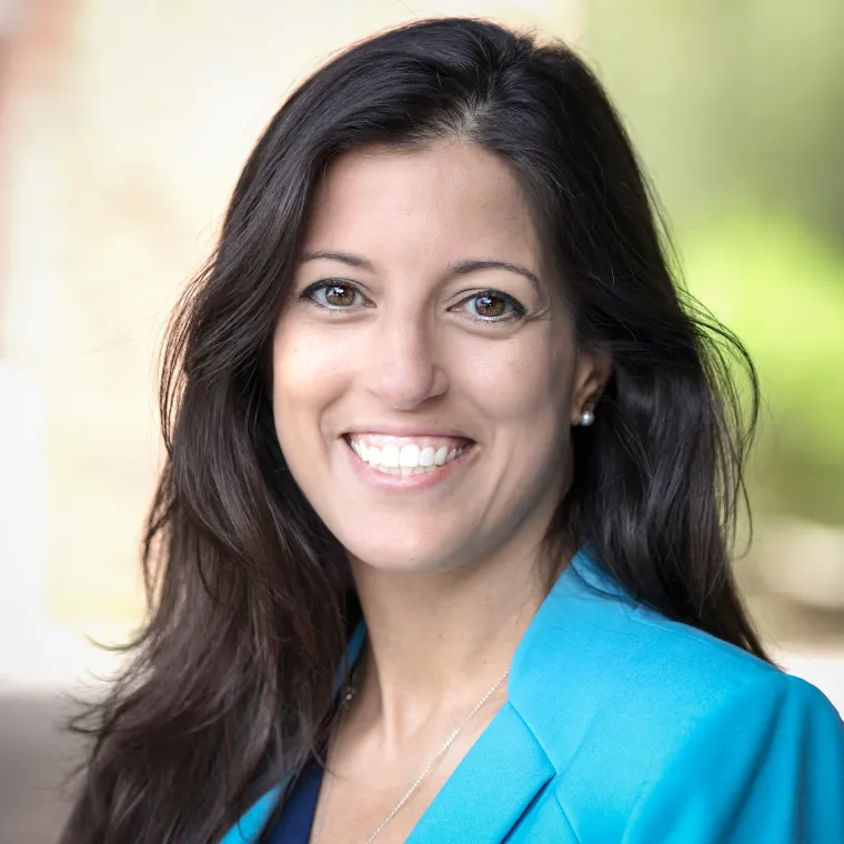 Smiling woman with long, dark hair in turquoise jacket