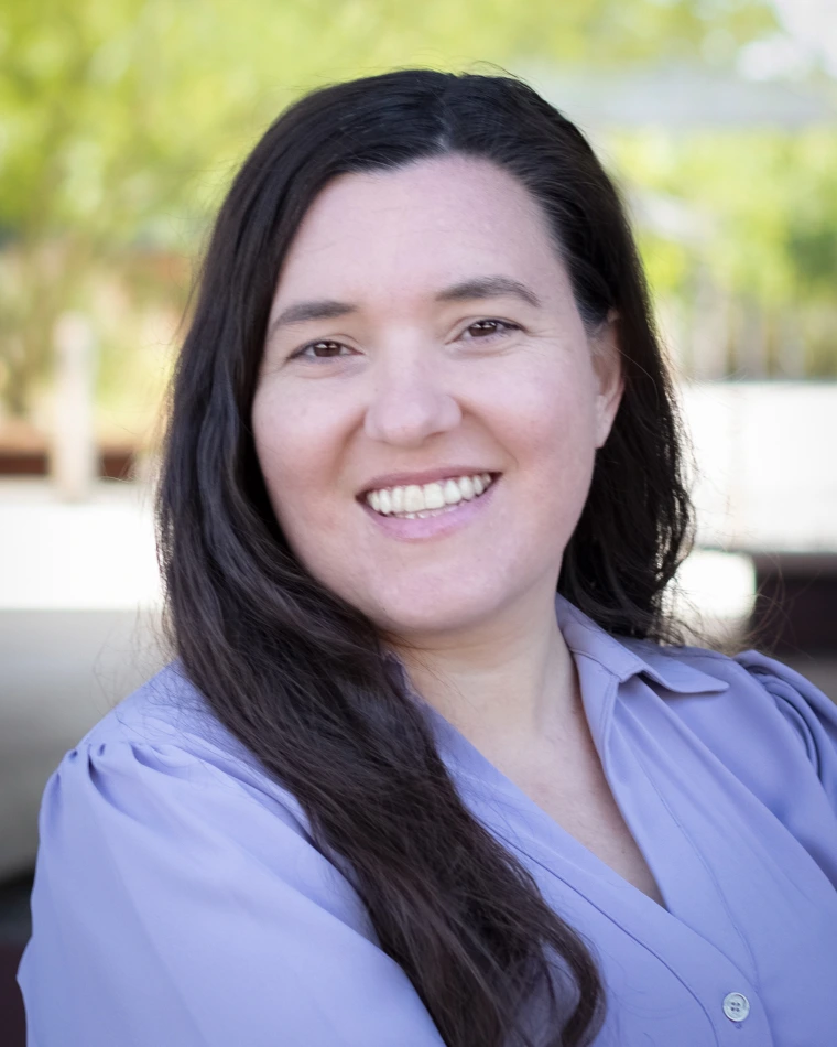 long, brown-haired smiling woman in lavendar button-down