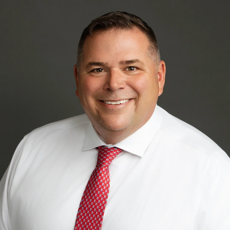 smiling man wearing a white collared shirt and red with white pattern tie