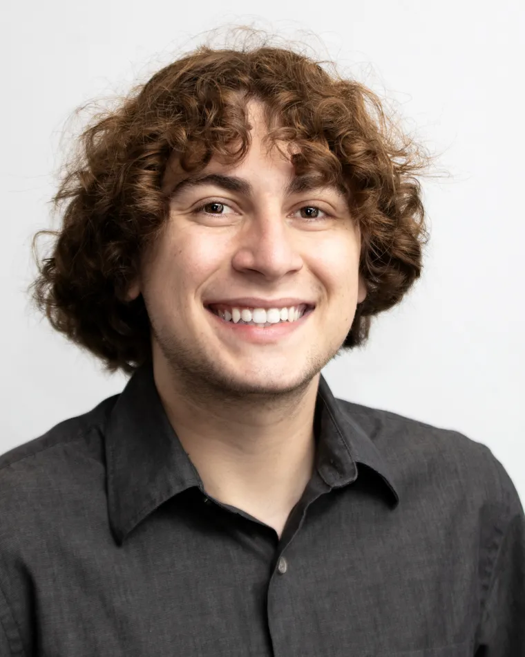 portrait of Michael Pisetsky against a light gray background, wearing a black button down shirt and smiling