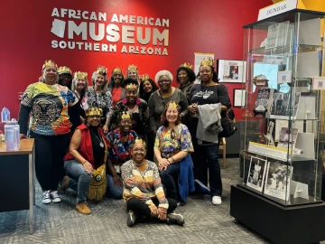 A group wearing crowns poses for a picture in the African American Museum of Southern Arizona.