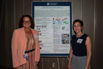 Two people stand on either side of a research poster