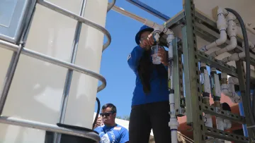 A Diné College student demonstrates use of the water filtration system.