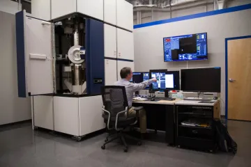 Tom Zega points at image on computer screen, showing images from transmission electron microscope