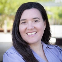 long, brown-haired smiling woman in lavendar button-down